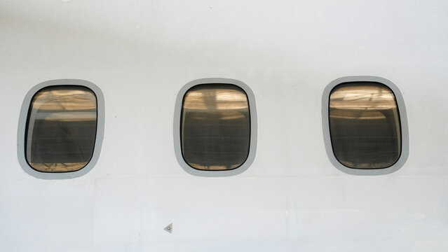 Close up of aircraft window with partial view of next window on white fuselage of commercial passenger airplane exterior detail of airplane body parts for aviation industry concept