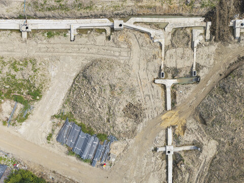 Aerial view of New Town infrastructure construction site featuring concrete foundations, earth mounds, and bundles of pipes in Taiwan.