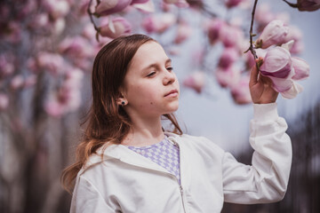 Yearold Girl Pausing Among Magnolia Branches, Daydreaming Expression With Closed Eyes And Gentle Breeze Through Pink Blooms © Evgeniia Biriukova