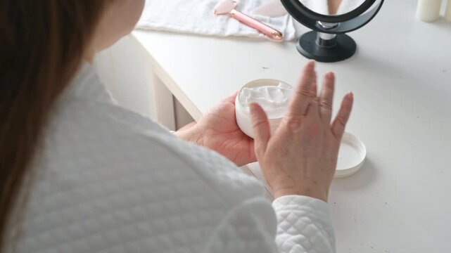 close up of woman opening cream jar during skincare routine at home