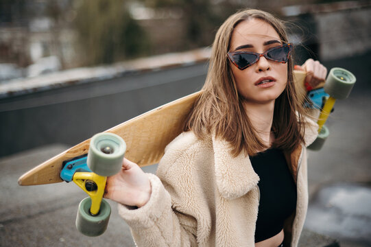 Stylish Woman with Skateboard on Rooftop