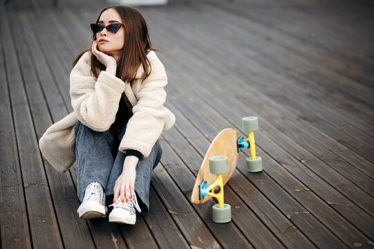 Female hipster sitting on rooftop near skateboard