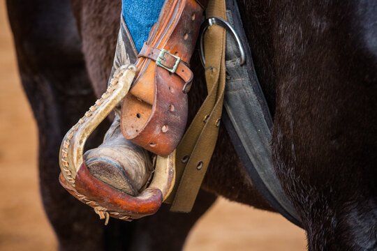 Closeup of a boot inside a stirrup of a horseback rider riding a