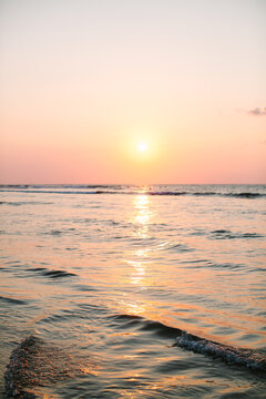 Surfers waiting for waves in the tranquil ocean at sunset