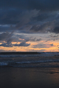 Surfer riding wave at dramatic tropical sunset, Canggu, Bali