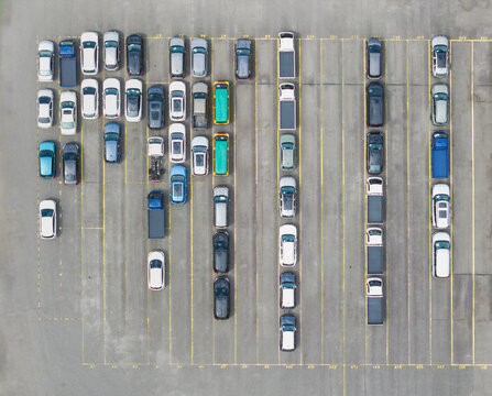 Aerial view of a car dealer inventory with rows of colorful vehicles and trucks parked on an asphalt lot with yellow lines in Taiwan.