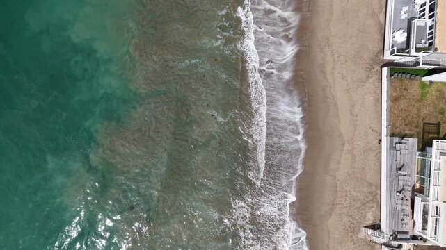 Cinematic daytime aerial drone footage captured from a top-down bird&rsquo;s-eye perspective hovering over the California coastline.