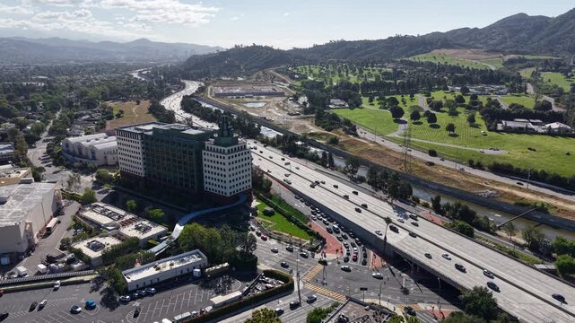 Cinematic daytime aerial drone footage captured over Burbank featuring a smooth reverse dolly pulling away from the Ventura 134 Freeway.