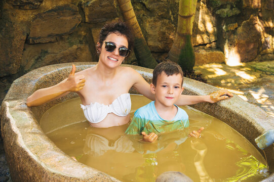 happy woman and son are relaxing in a mud bath at spa in a resort on vacation. Natural hot mineral mud baths with clay for skin care in Vietnam in Asia