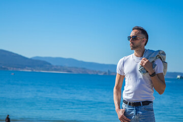 Casual man with jacket over shoulder against a sea background