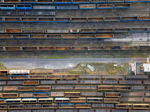 Aerial view of freight train wagons parked on multiple parallel tracks at a railway cargo terminal with a central paved road Warsaw, Masovian Voivodeship, Poland.