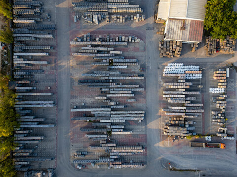 Aerial view of neatly organized rows of construction materials and stone pallets in an industrial storage yard with a truck and surrounding trees Warsaw, Masovian Voivodeship, Poland.