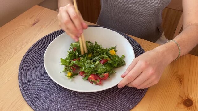 A Woman Enjoying a Healthy Salad While Using Chopsticks in Her Home