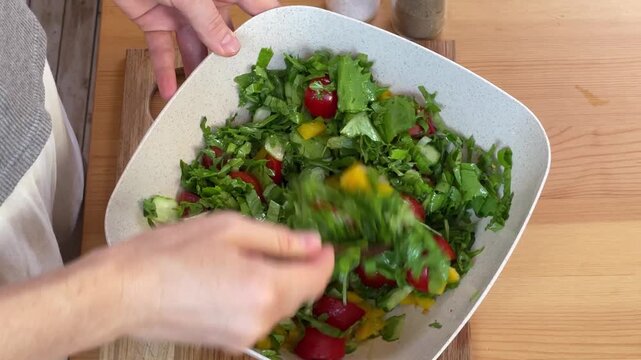 Making a Fresh Salad with Mixed Greens and Various Vegetables
