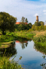 Calm river in Supraśl, Poland, vertical view with reflection, green banks and blue sky, peaceful Podlasie landscape © Anna