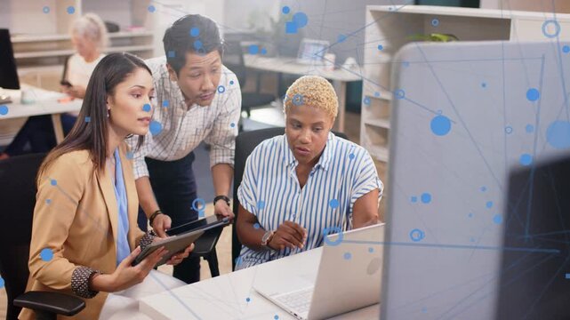 Team using tablet while tapping laptop, generating blue overlays over screens for business