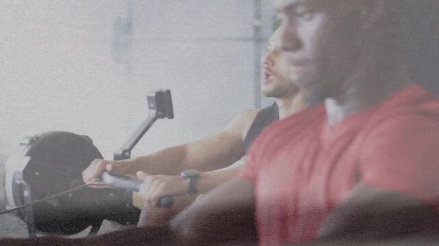 Three men gripping erg handles and initiating stroke, driving legs and pulling for fitness training