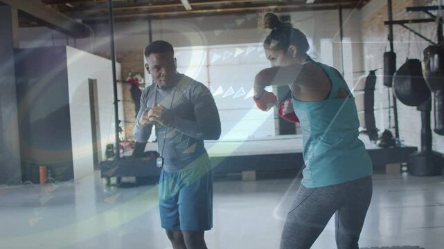 Trainer cueing trainee with timer, trainee wearing red wraps throwing jabs and crosses for fitness