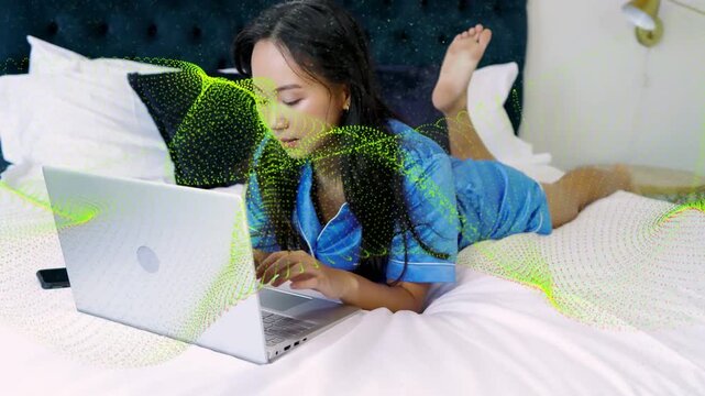 Woman typing on laptop bed phone for business green overlay obscuring screen camera pulling back