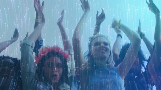 Two front women moving to music beat, raising arms, smiling and clapping under translucent rain