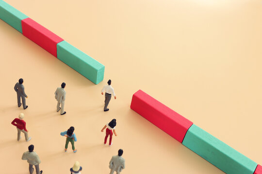 Concept image of leadership. Group of miniature people walking towards obstacle