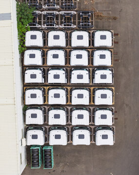 Aerial view of white truck cabins neatly arranged in a grid at a manufacturing facility with chassis components and tires Taiwan.