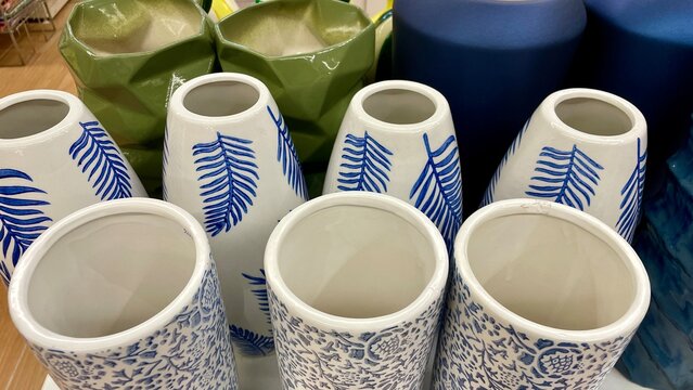 Collection of ceramic vases with blue leaf patterns and green geometric planters, pottery display