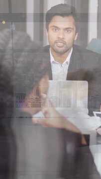 Vertical video: Team reacting to offscreen hand, using laptop, smiling in biz mtg, glass overlay