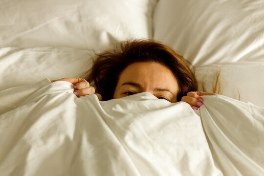 Playful person covering face with duvet