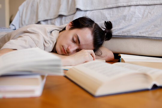 Tired student taking nap among scattered books