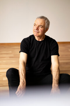 Senior man sitting on floor resting after yoga practice