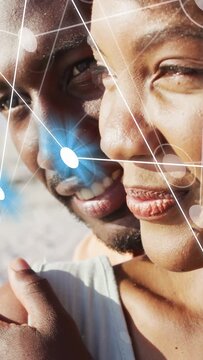 Vertical video: Woman turning and man leaning in on sand causing AR grid blue node mapping bond