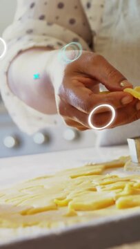 Vertical video: Home baker lifting cut dough adjusting for baking as blue icons float over hands