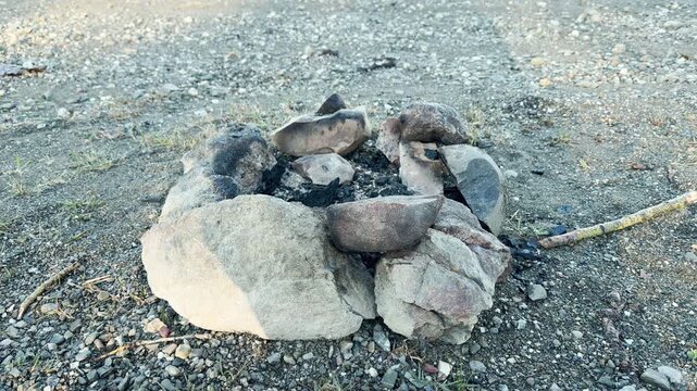 A ring of heavy stones holds burnt charcoal on a wide pebble beach. The cold ashes stir a nostalgic feeling of warmth shared under the open sky. It is a quiet, lonely spot for reflection.