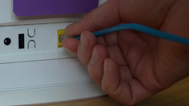 Close up of hand plugging ethernet cable into router port. Concept of internet connection, network, technology and communication.