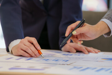 Naklejka premium Close up of business people hands pointing at marketing report graphs during meeting.