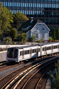 Urban transit scene as metro train approaches tracks and railway lines in Oslo Norway conveying daily commute and transportation network