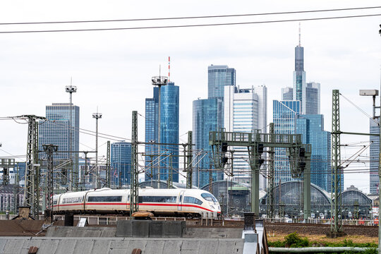 Urban railway tracks scene with train and station foreground framing Frankfurt Germany skyline emphasizing transportation infrastructure and mobility