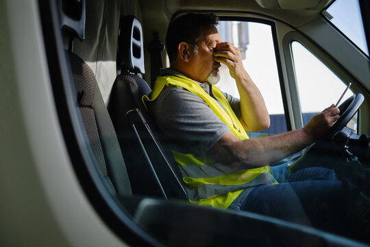 Mature man covering eyes experiencing stress in truck
