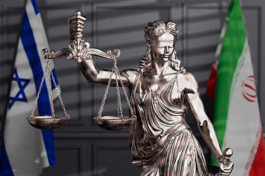 International Justice And Middle East Conflict. Femida Statue With Scales Between Israeli And Iranian Flags In Blurred Courtroom Interior. 3d Rendering