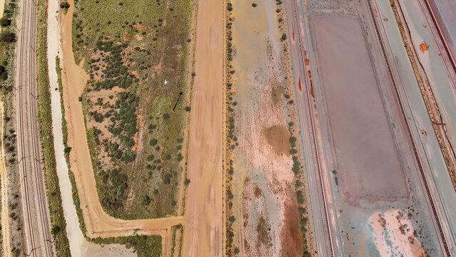 Aerial view of rusty-red earth and linear drainage patterns create an abstract canvas of industrial tones and textures, Africa.