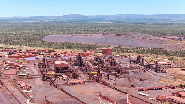 Aerial view of a vast industrial complex stretching across the landscape with reddish-brown tones contrasting against the distant green horizon, Limpopo, South Africa, Africa.