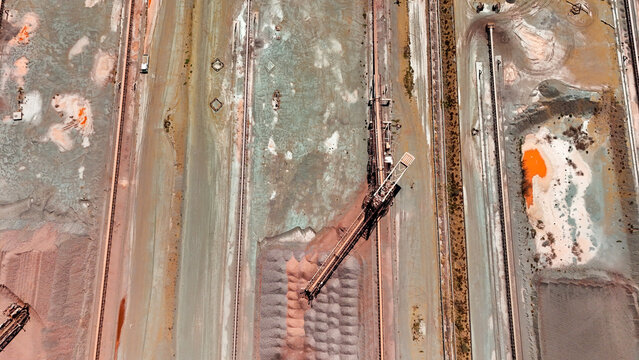Top down aerial of mining site with railway tracks, industrial textures and extraction landscape.