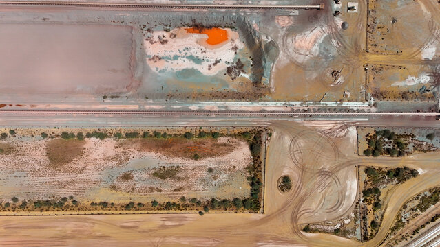 Aerial view of parched earth and vibrant orange pools, showcasing a landscape shaped by both nature and industry, Africa.