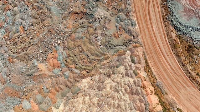 Aerial view of layered earth tones create a tapestry of textures, punctuated by the stark contrast of a ruddy road slicing through the landscape, Africa.