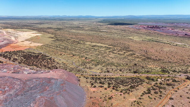 Aerial view of the stark contrast between the rust-colored earth and the sparse vegetation under a clear sky, North West, Africa.
