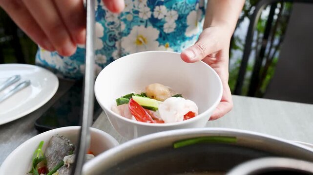Serving Spicy Thai Tom Yum Seafood Soup into a White Bowl