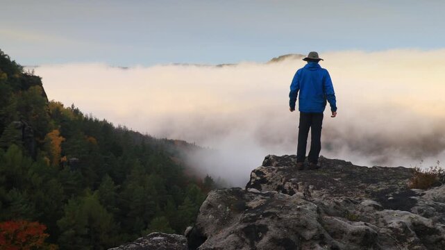 lonely man on a rock above the autumn canyon of the Elbe river with fog - Bohemian Switzerland park