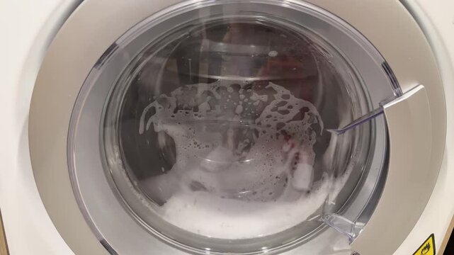 Slow Motion View of Red Clothing Rotating in a Washing Machine Drum