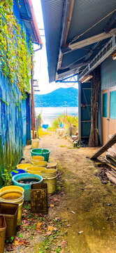 滋賀県・沖島の民家の間から望む琵琶湖と路地に並ぶ漁具の風景